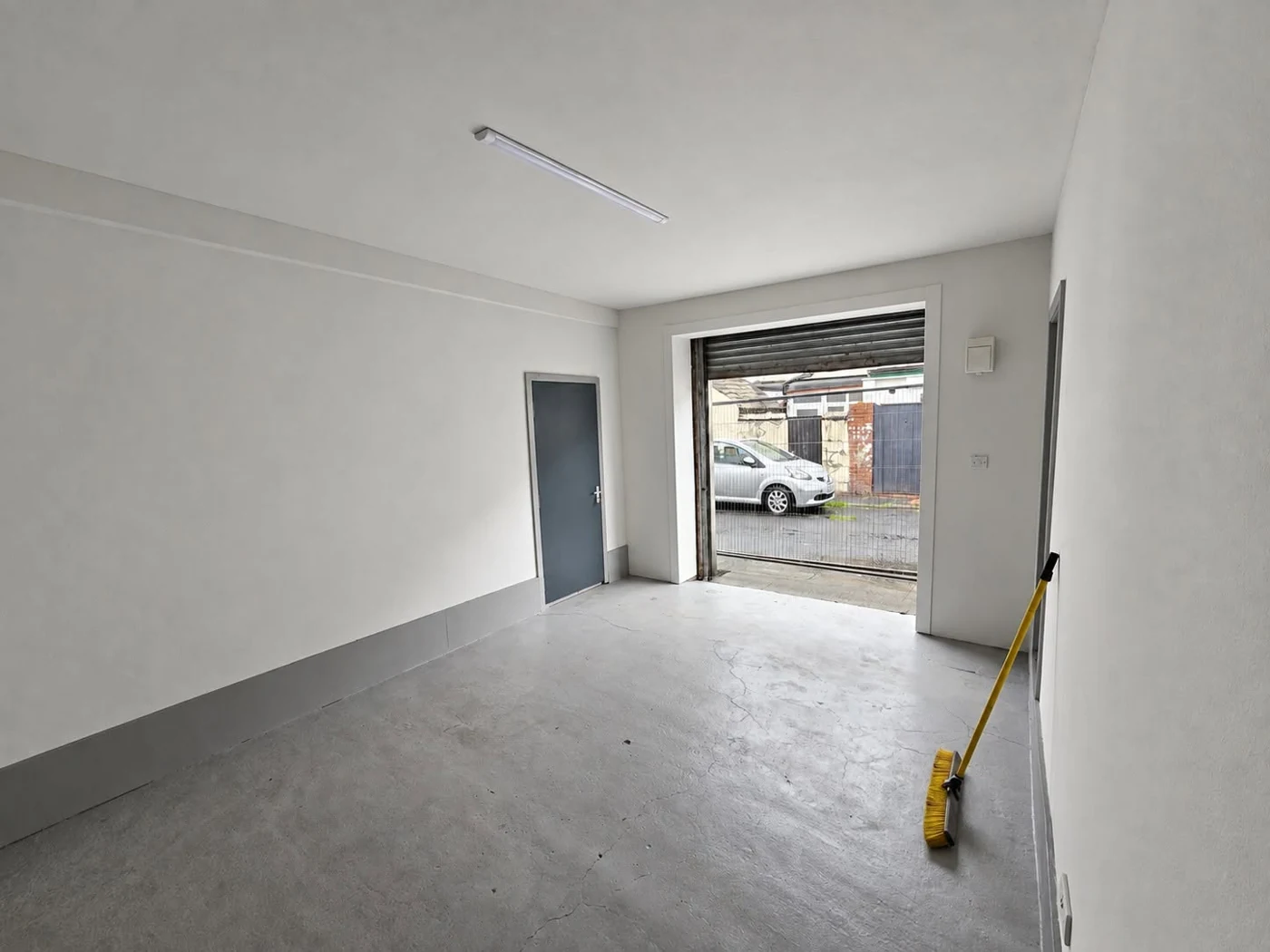 Unit at The Rock Factory Blackpool with grey flooring, overhead lighting, a personnel door and an open roller shutter